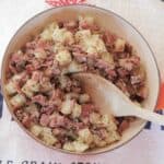 Skillet of corned beef hash and a wooden spoon