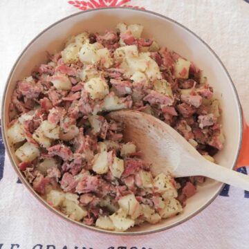 Skillet of corned beef hash and a wooden spoon
