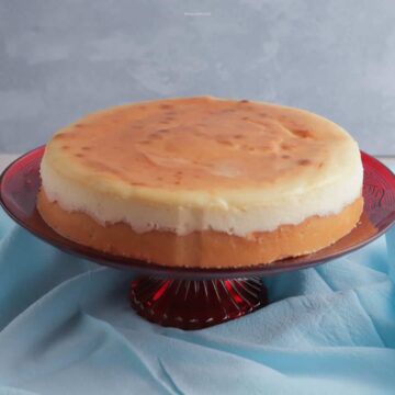 New York style cheesecake on a red pedestal cake stand