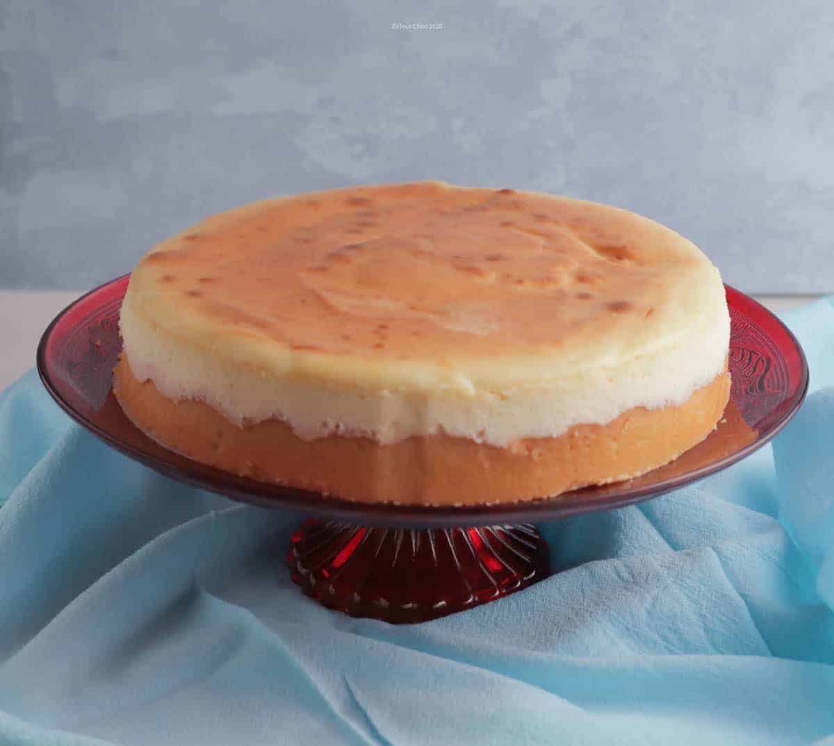 New York style cheesecake on a red pedestal cake stand