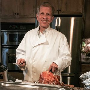 Chef Richard in a chef's jacket carving a turkey