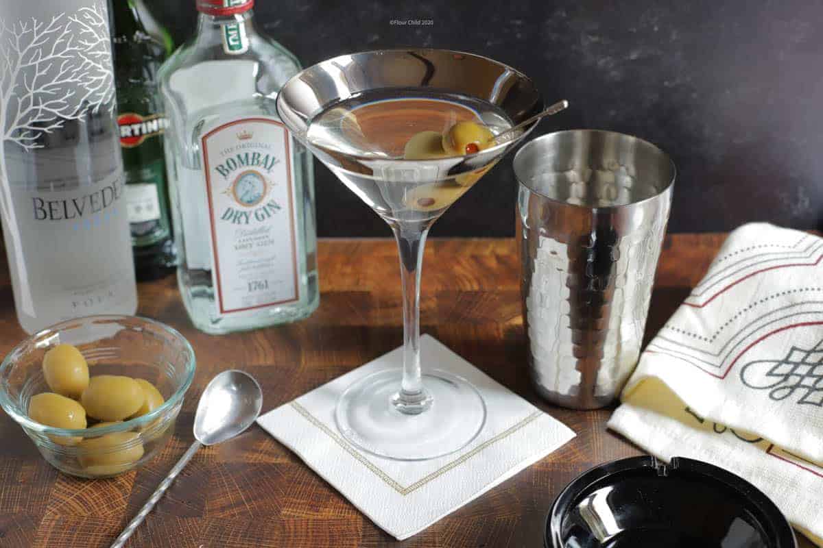 Martini cocktail bar set in a glass with olives and vodka or gin bottles.