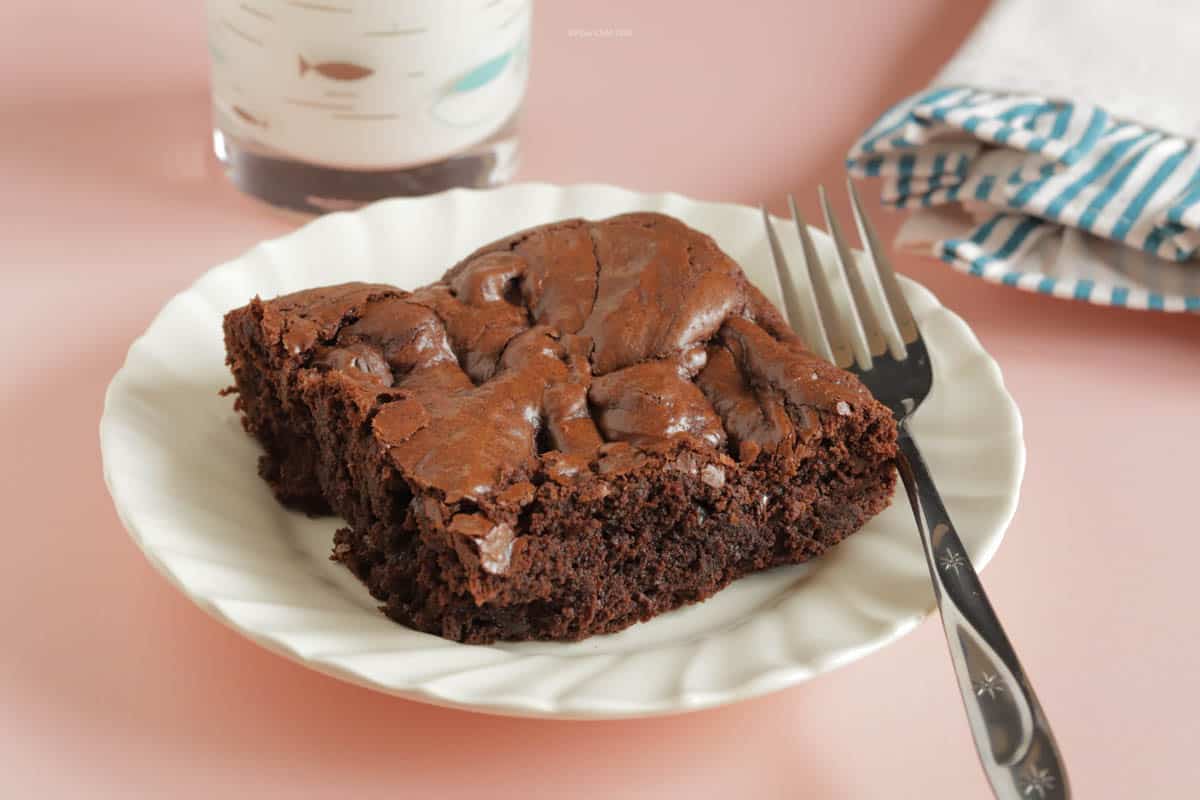 30 Minute Fast and Easy Brownies on a white plate with a fork. Glass of milk and napkin next to the plate.