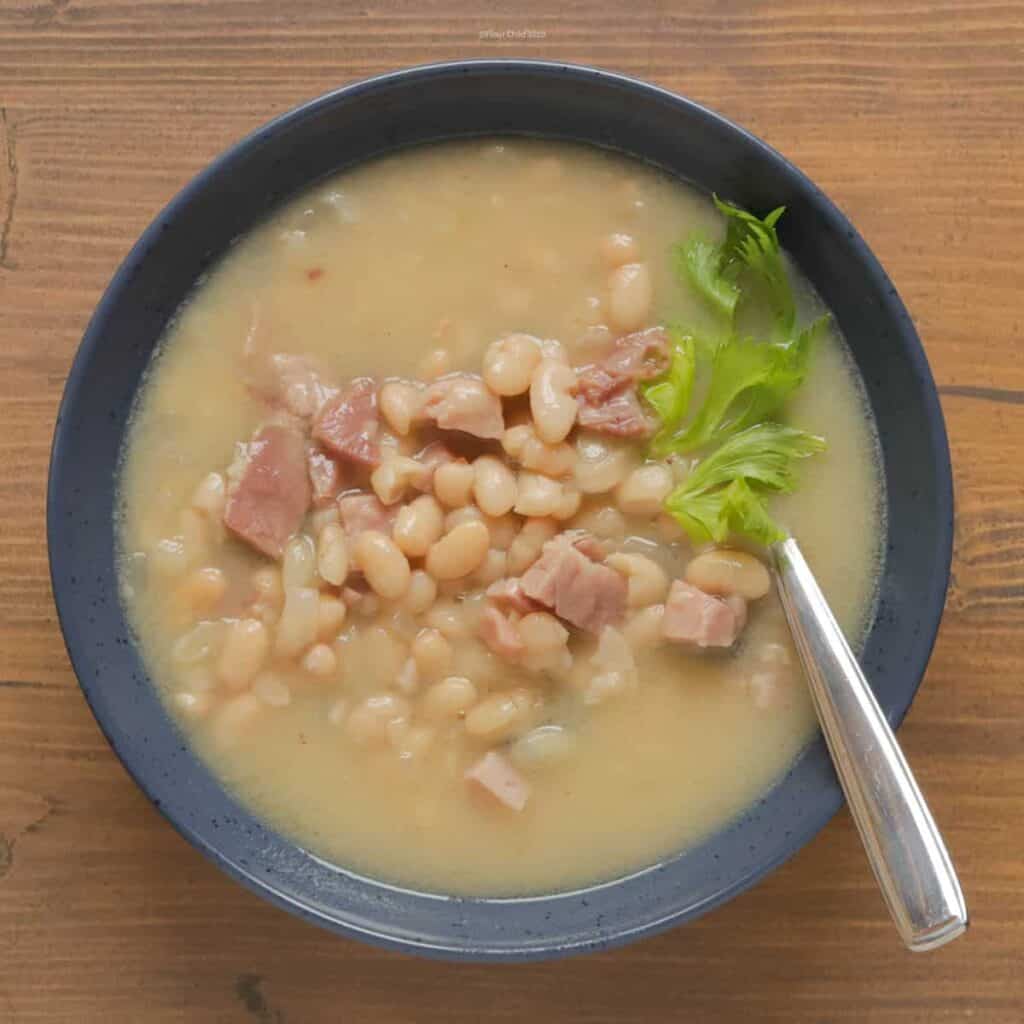 Traditional Navy Bean Soup in a blue bowl with spoon.