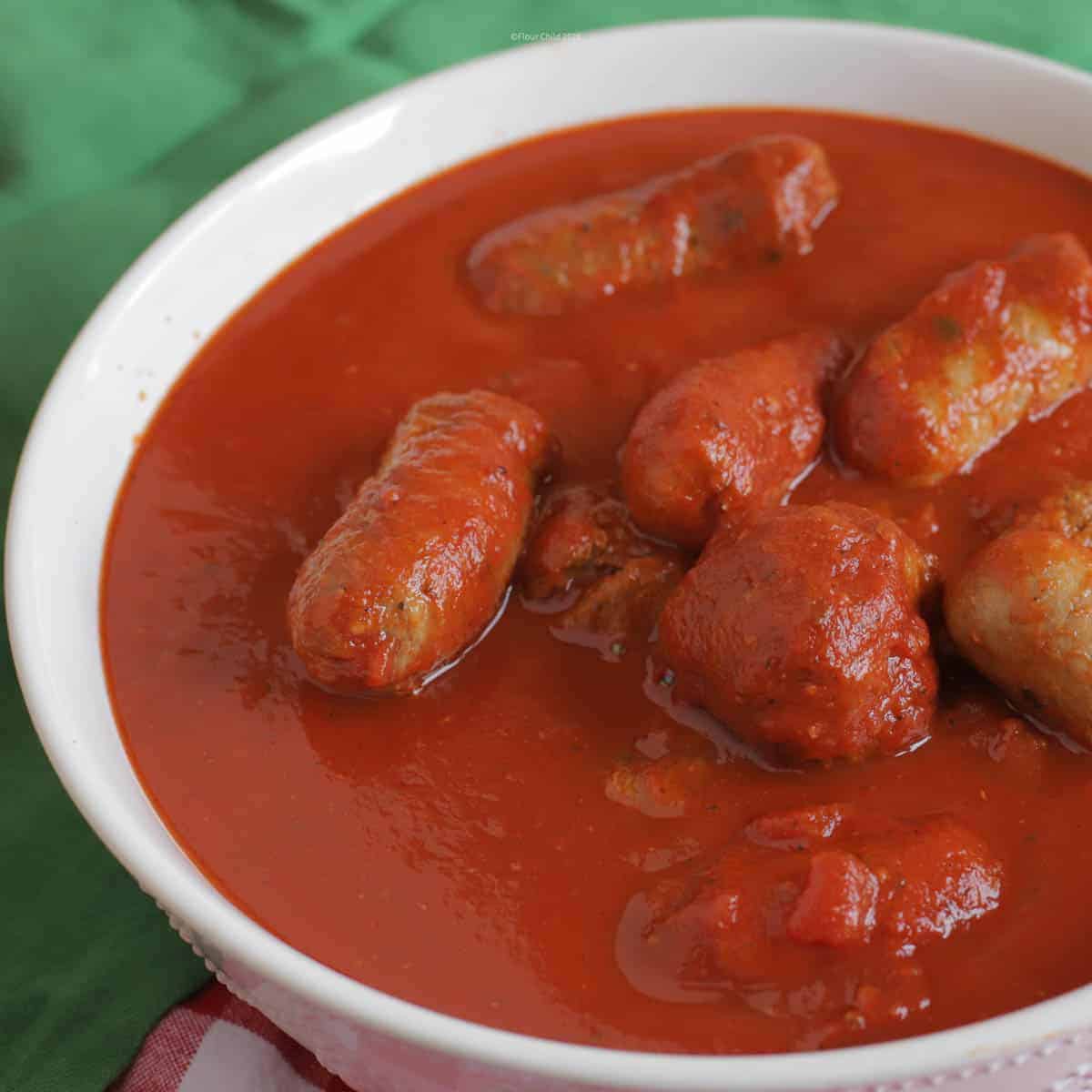 A bowl of red authentic Italian Sunday sauce with meatballs and Italian sausage inside