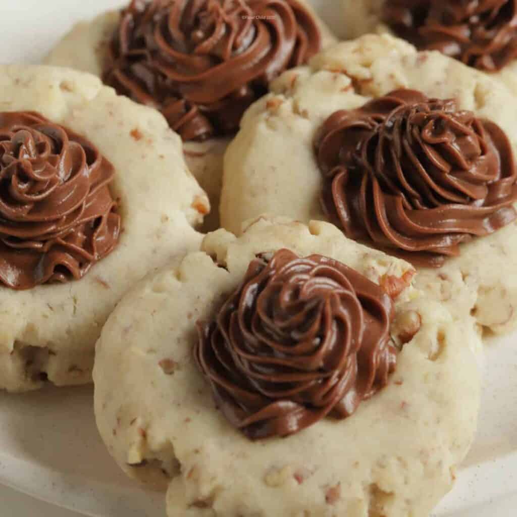 Four chocolate frosted pecan sandies cookies on a plate