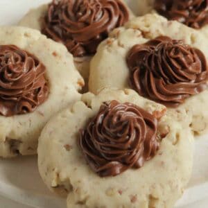 Four chocolate frosted pecan sandies cookies on a plate