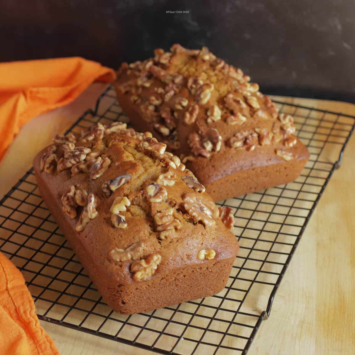 Two loaves of pumpkin bread on a cooling rack