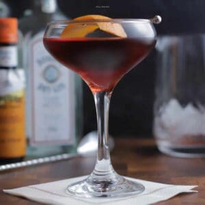 A close up cocktail in a coupe glass with a black background