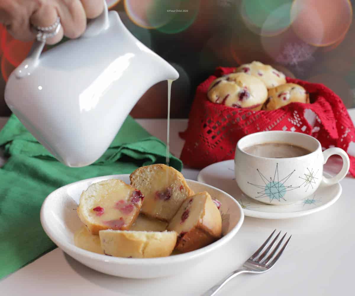 Dish of cranberry muffins with hot butter sauce being poured over the top.