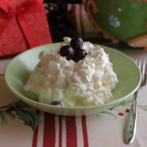 Cranberry whipped cream salad in a small serving dish, with three cranberries garnishing the top.
