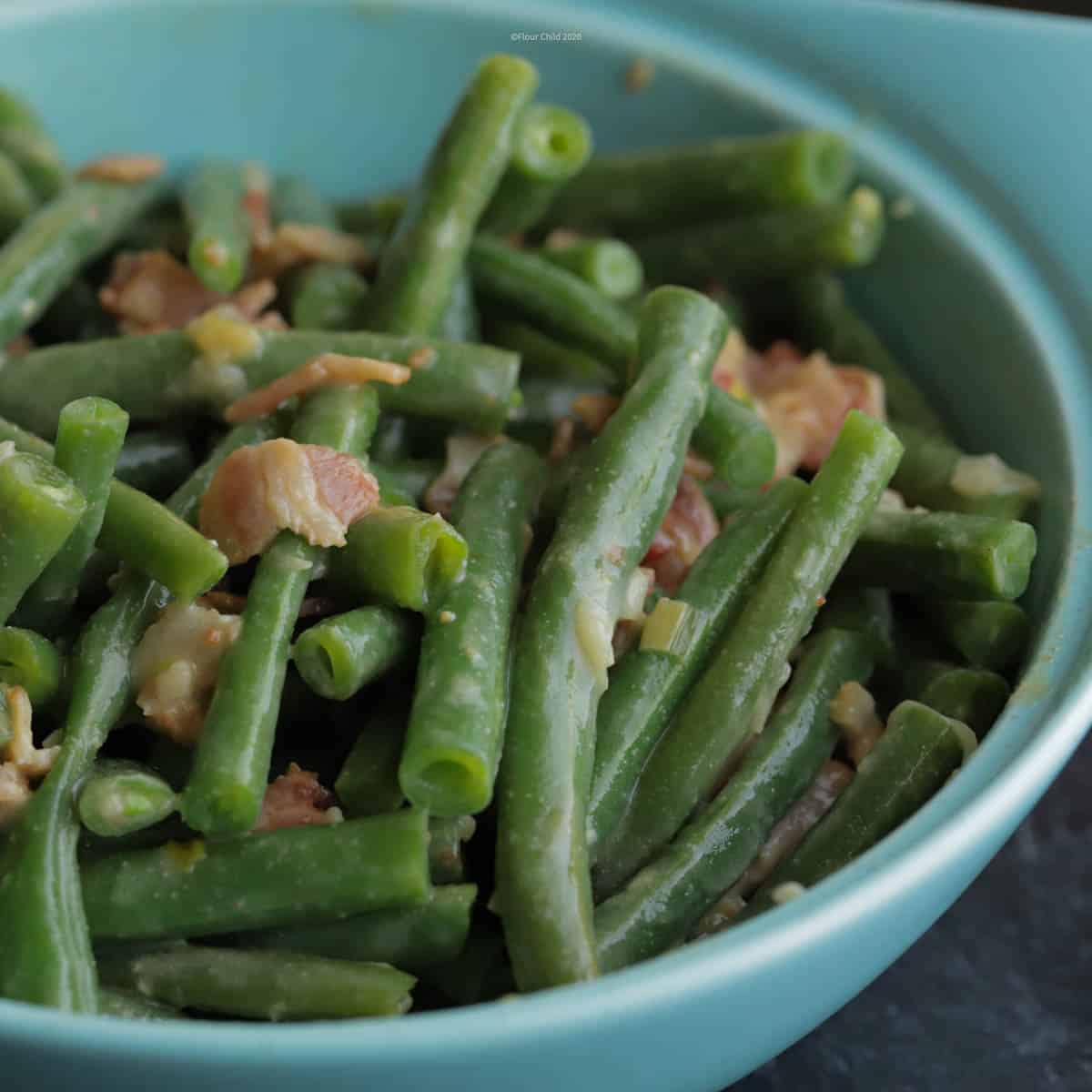 Bowl of fresh green beans dijon in a blue serving bowl