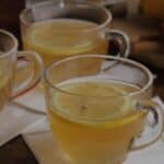 A close up of two hot toddies in clear glasses with lemon slices