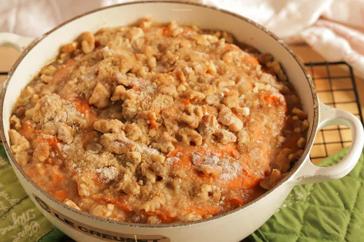 sweet potato casserole topped with pecans in a white le Creuset cast iron casserole dish