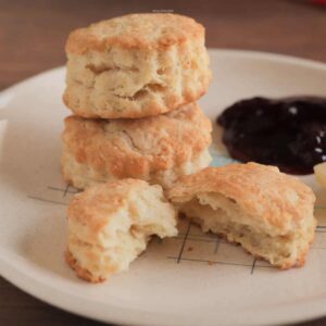 Biscuits stacked on a plate with butter and preserves