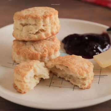 Biscuits stacked on a plate with butter and preserves