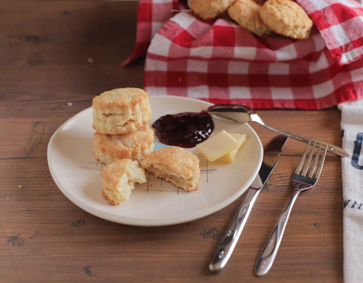 Biscuits stacked on a plate with butter and preserves