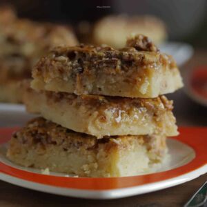 Three pecan pie bars stacked on a dessert plate