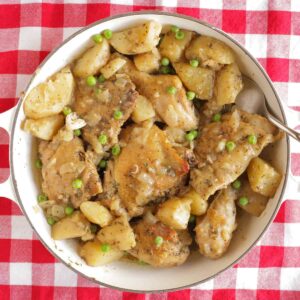 Chicken vesuvio in a serving dish sitting on top of a red checkered tablecloth