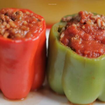 Green and red stuffed peppers sitting side by side on a plate