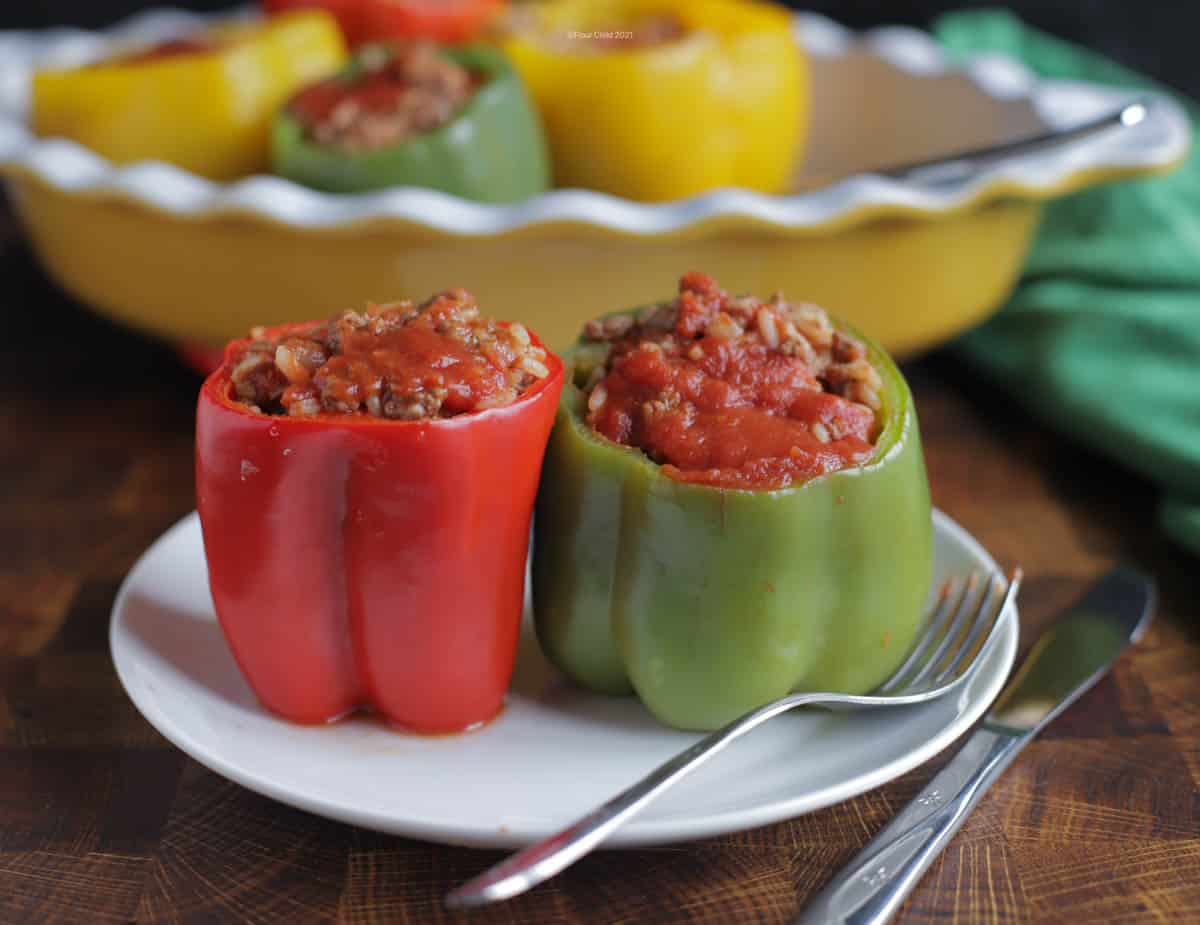A red and green stuffed bell pepper next to each other on a white plate