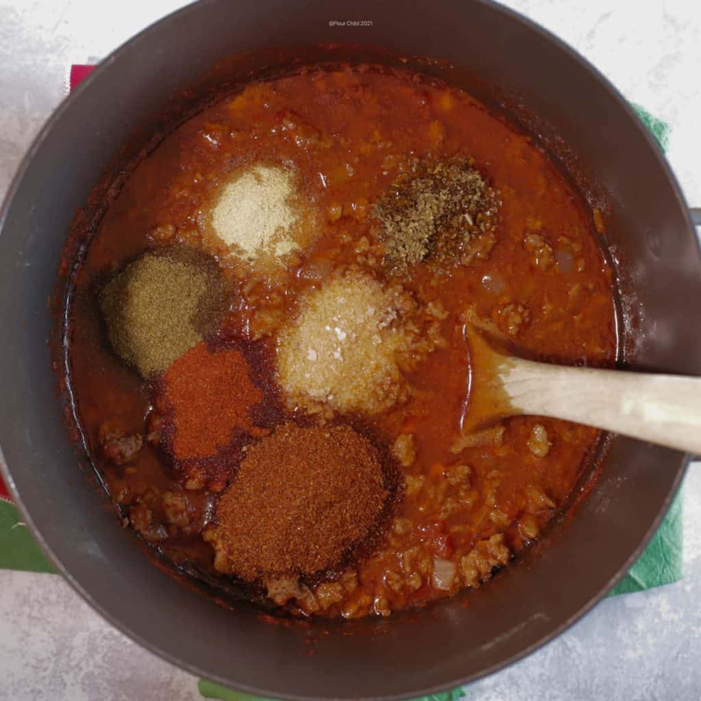 Adding the second seasoning of spices to the pot of chili
