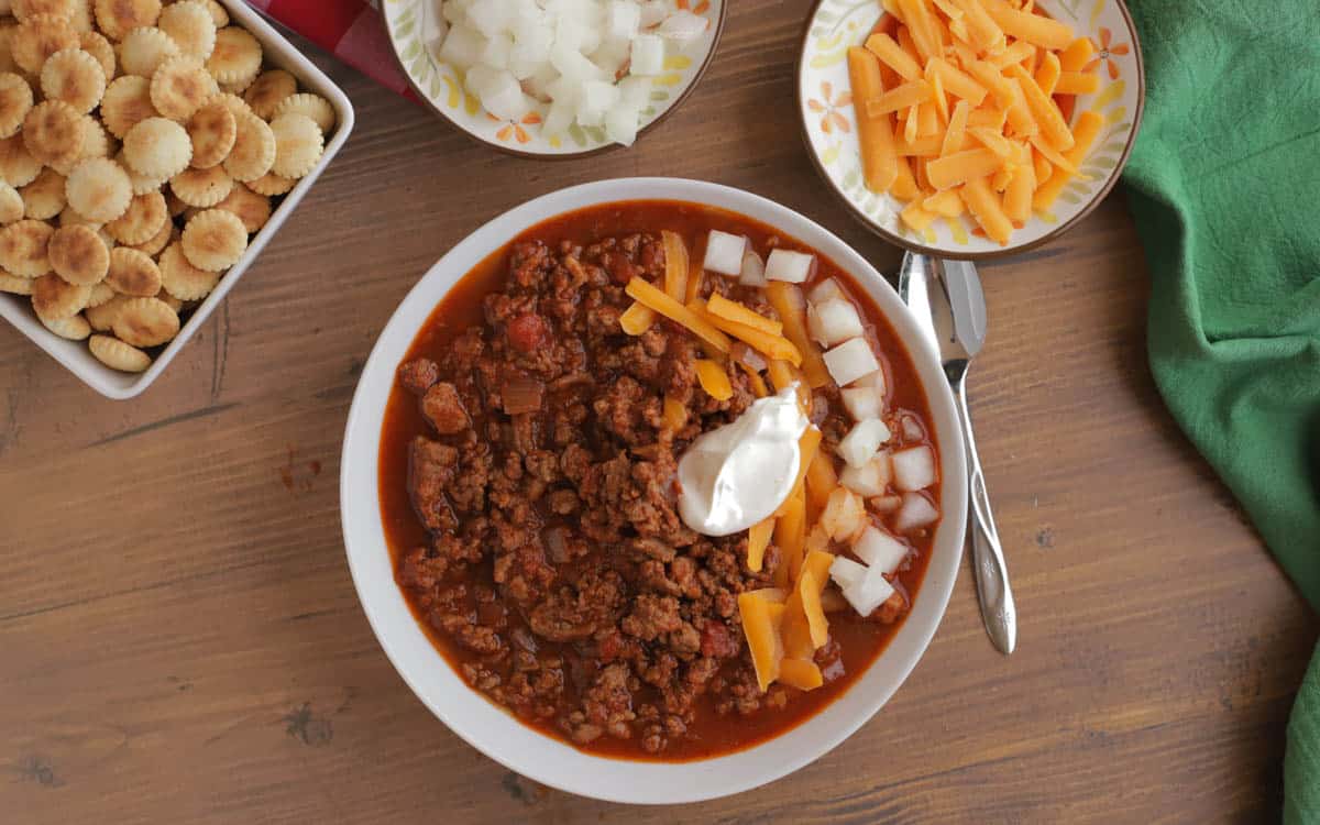 Bowl of chili topped with cheese, onions, and sour cream