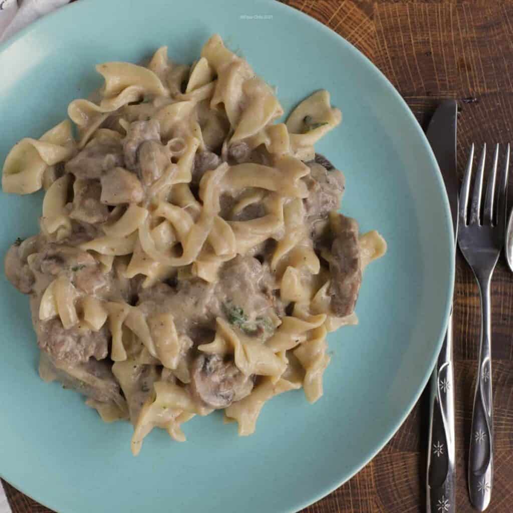 Homemade beef stroganoff on a blue dinner plate.
