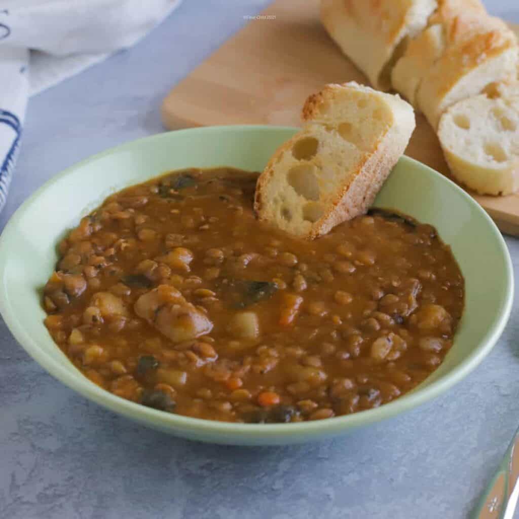 Bowl of simple lentil soup served with French bread on the side.