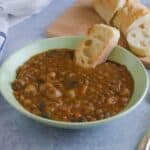 Bowl of simple lentil soup served with French bread on the side.