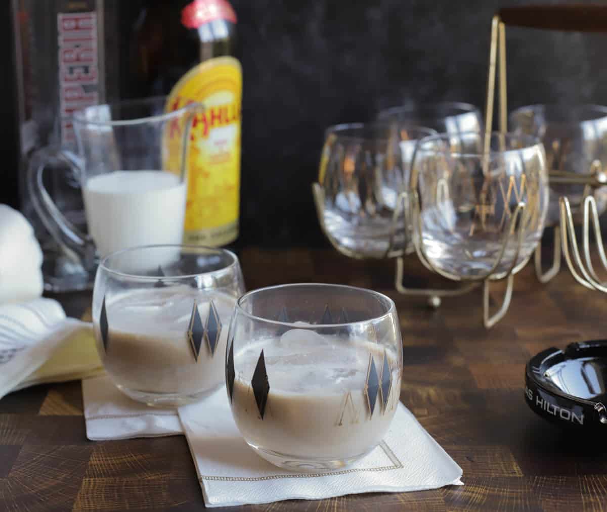 Two white russian cocktails with extra glasses