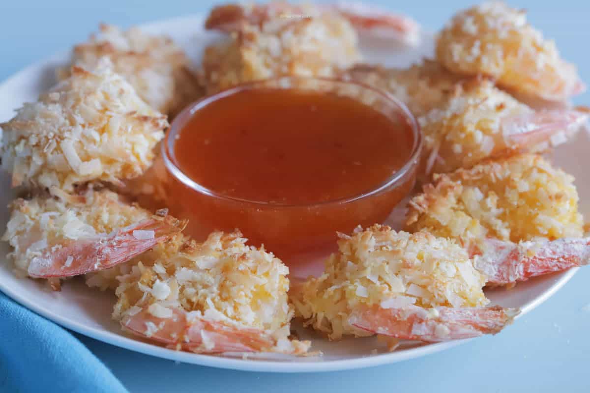 A plate of coconut shrimp with a bowl of  apricot dipping sauce in the center