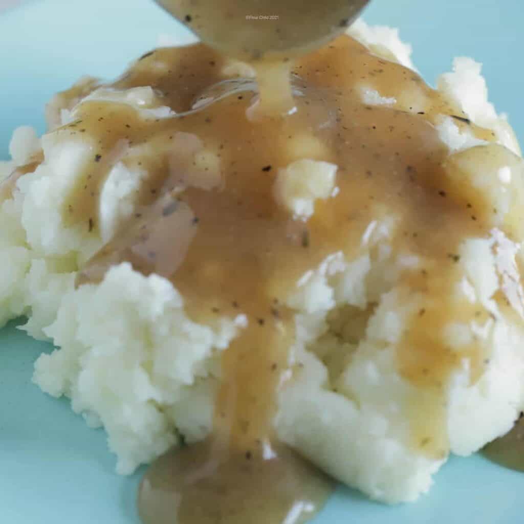 Beef gravy being labeled over a serving of mashed potatoes.