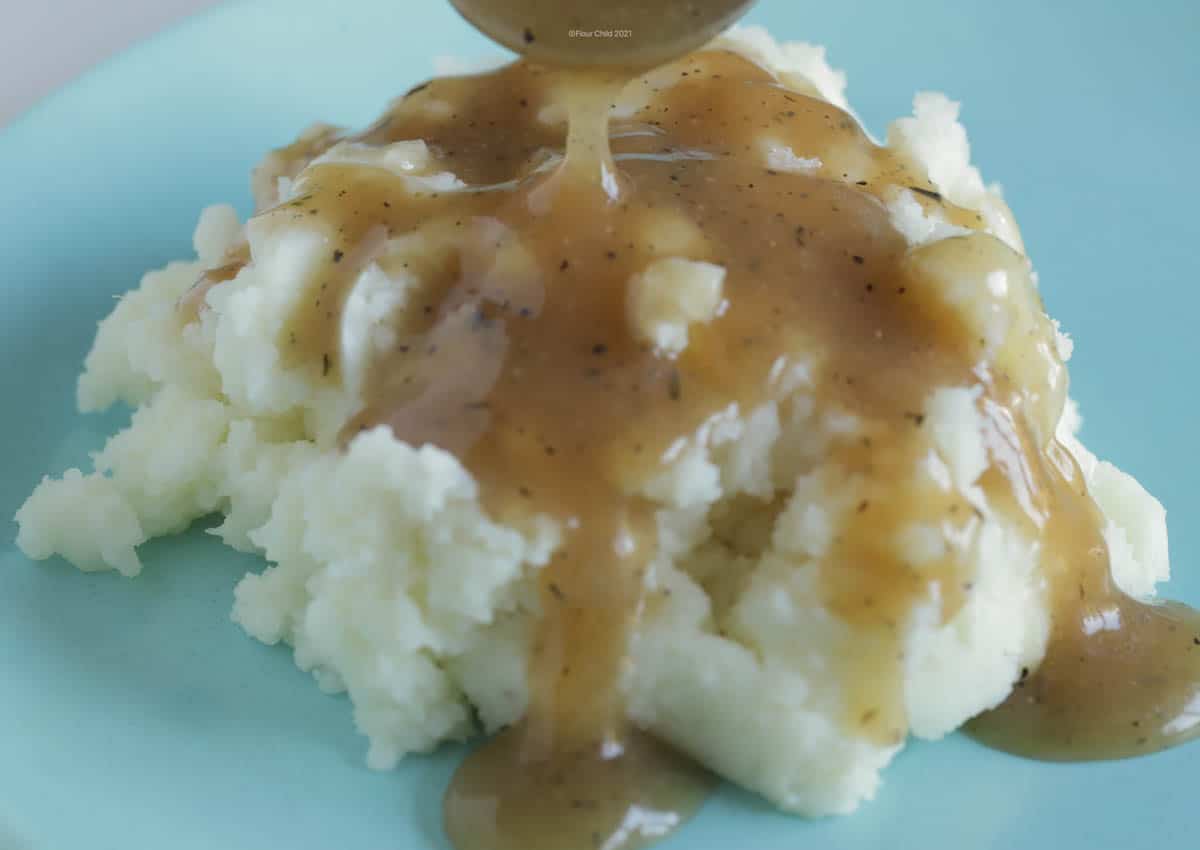 Beef gravy being labeled over a serving of mashed potatoes