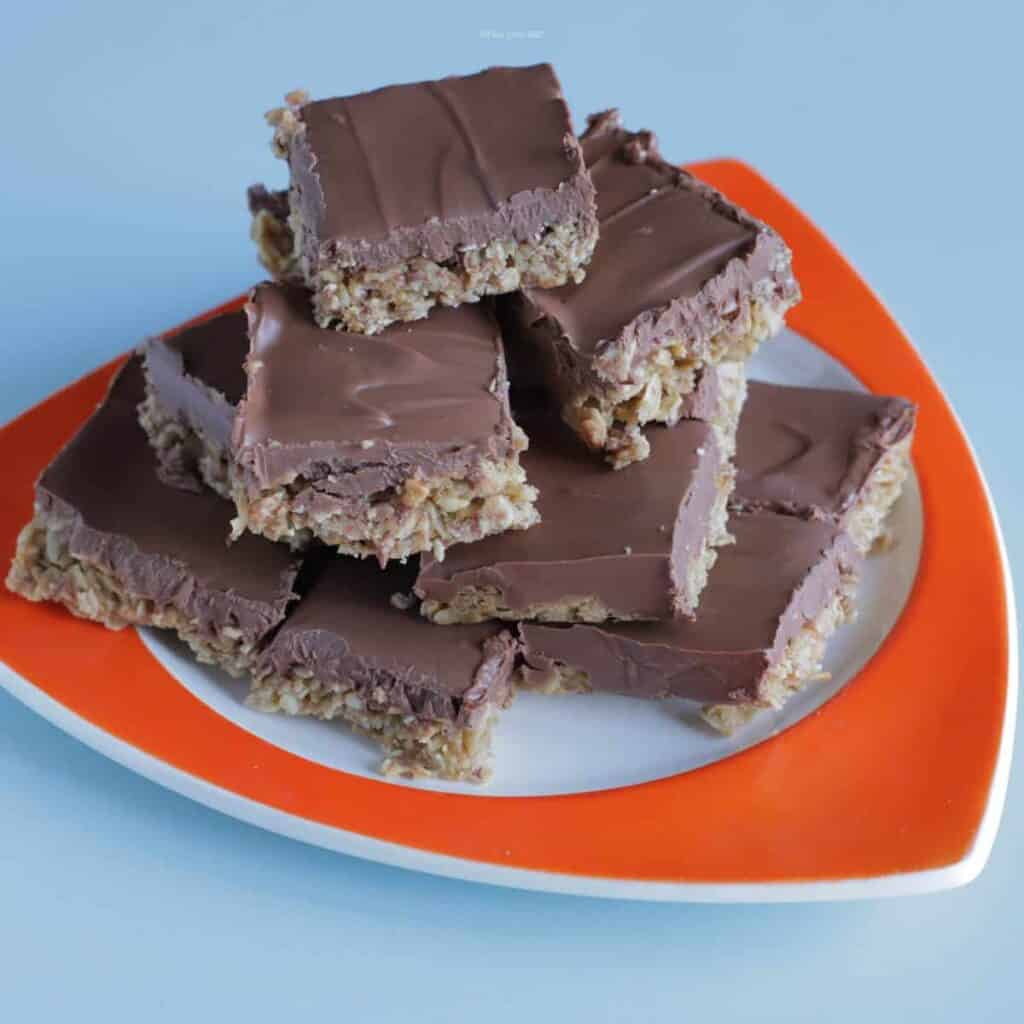 A stack of peanut butter oatmeal squares on an orange plate.