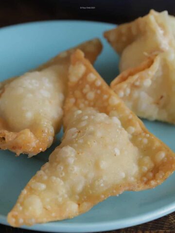 Three pieces of crab rangoon on a blue plate.