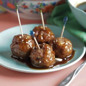 Four teriyaki meatballs on a blue plate.