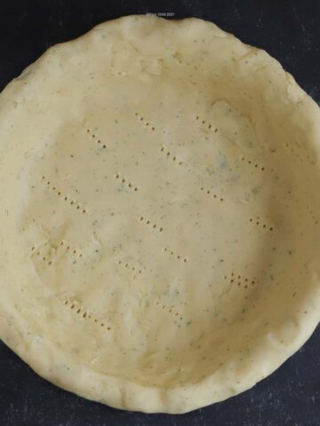 An empty quiche crust in a pie plate.