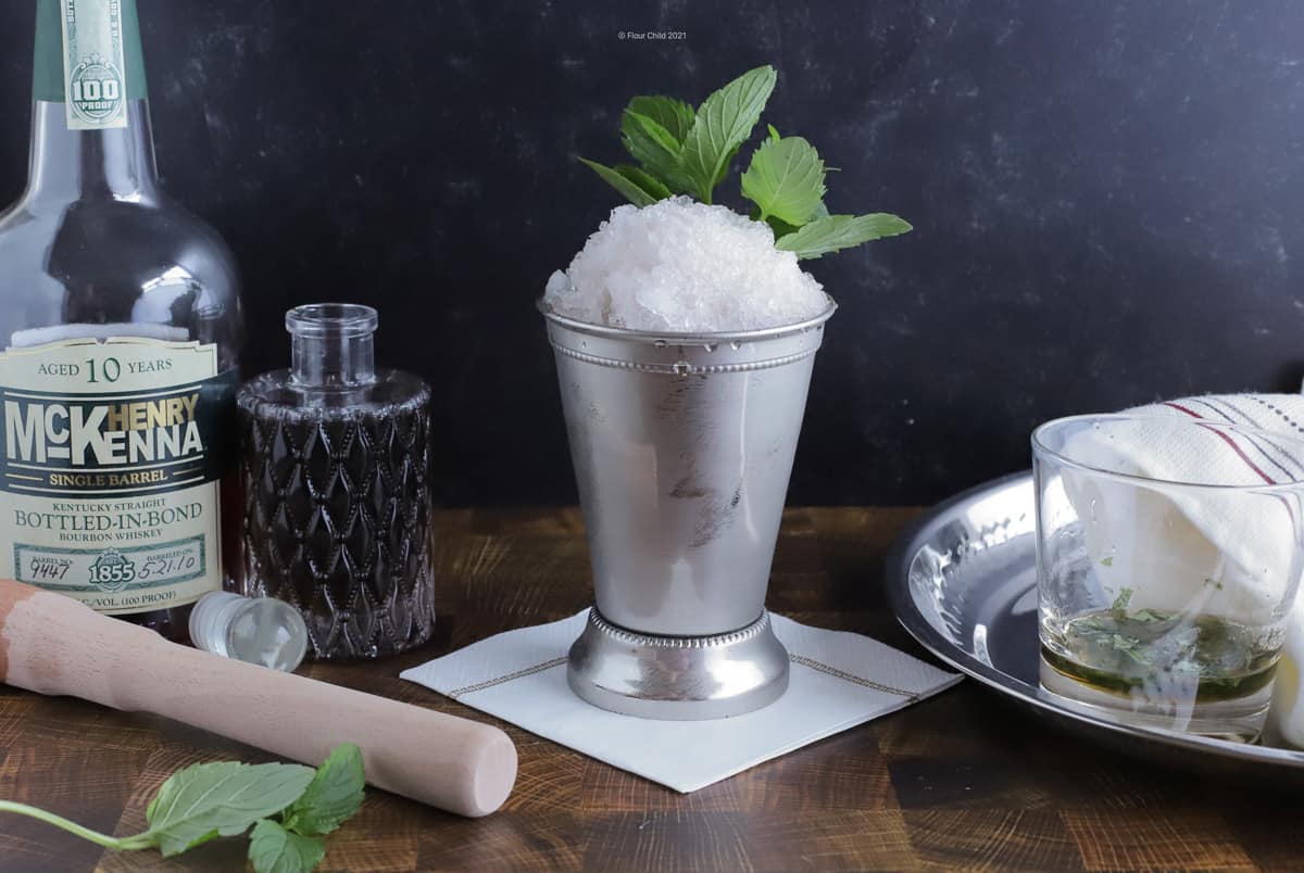 mint julep in a silver cup with a bottle of McKenna bourbon
