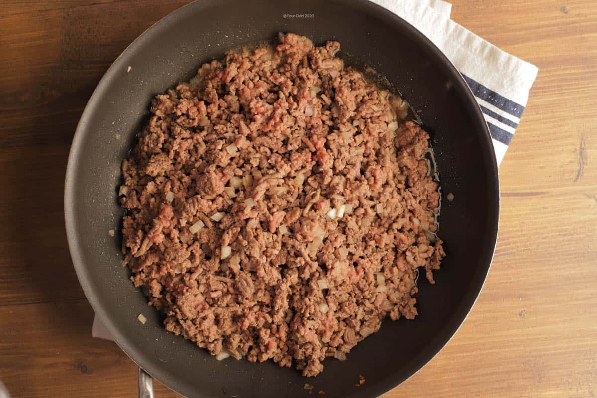 Ground beef browning in a cast iron skillet