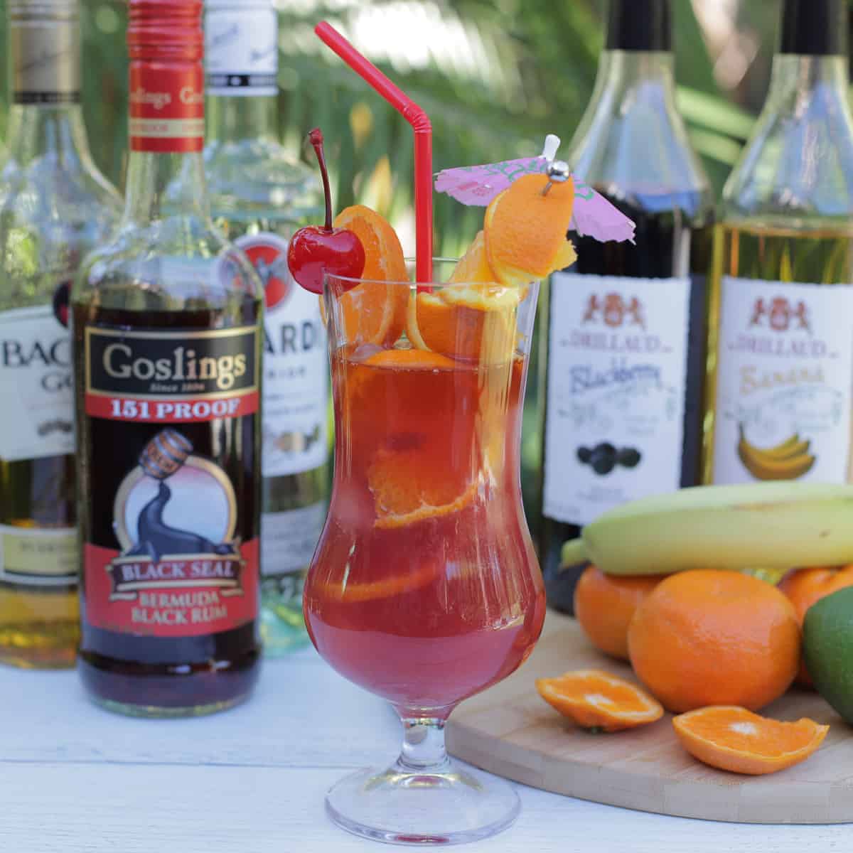 A Rum Runner Cocktail in a hurricane glass with ingredients.