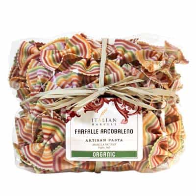 Rainbow farfalle pasta wrapped in a clear cellophane package with a raffia bow tied around the center