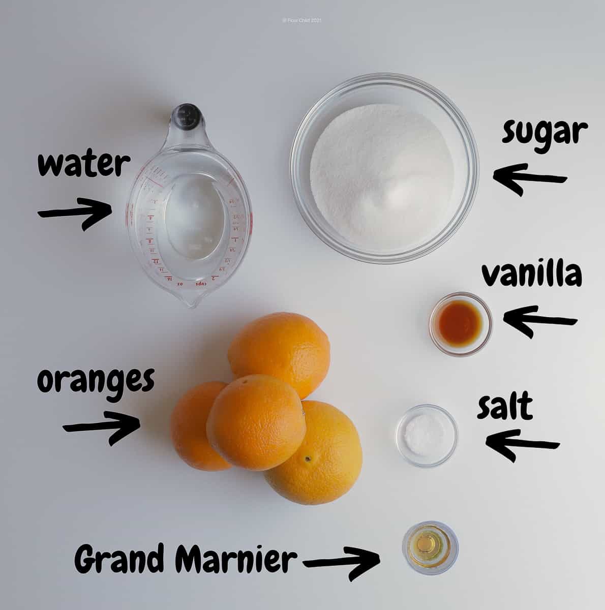 Ingredients for candied orange peel set on a countertop, including water, sugar, oranges, vanilla, salt and Grand Marnier