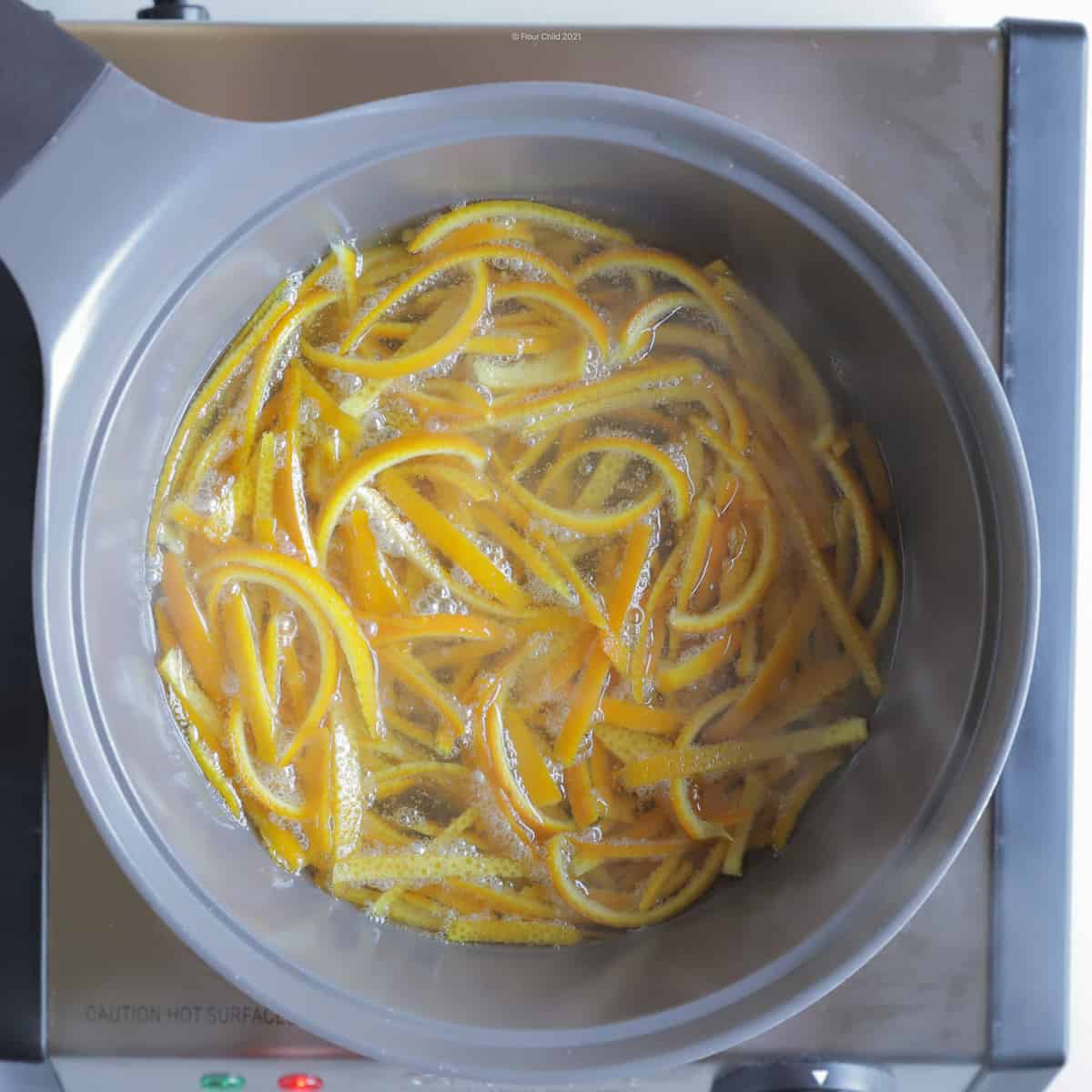 Orange peel resting in sugar and vanilla before removal to cooling rack