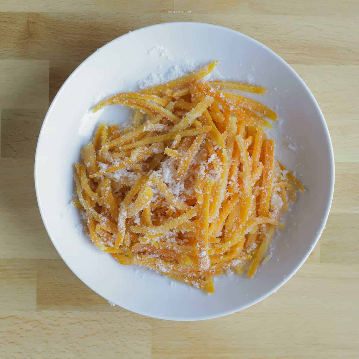 Candied orange peel piled in a white bowl, ready to use as a garnish or eat as a candy