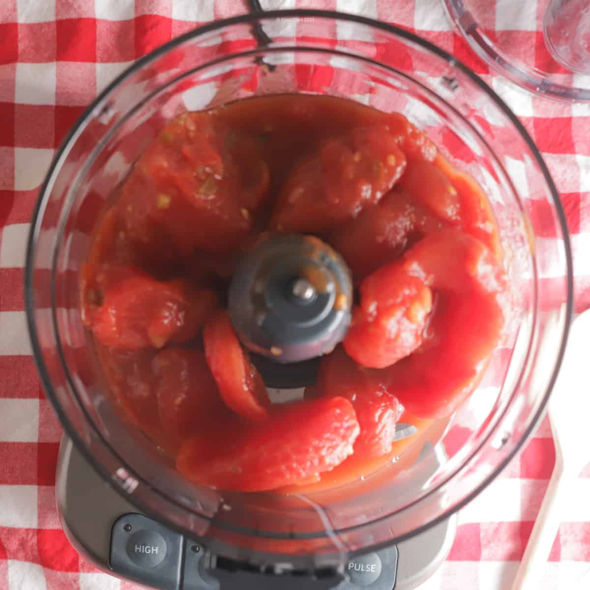 Whole stewed tomatoes inside a food processor