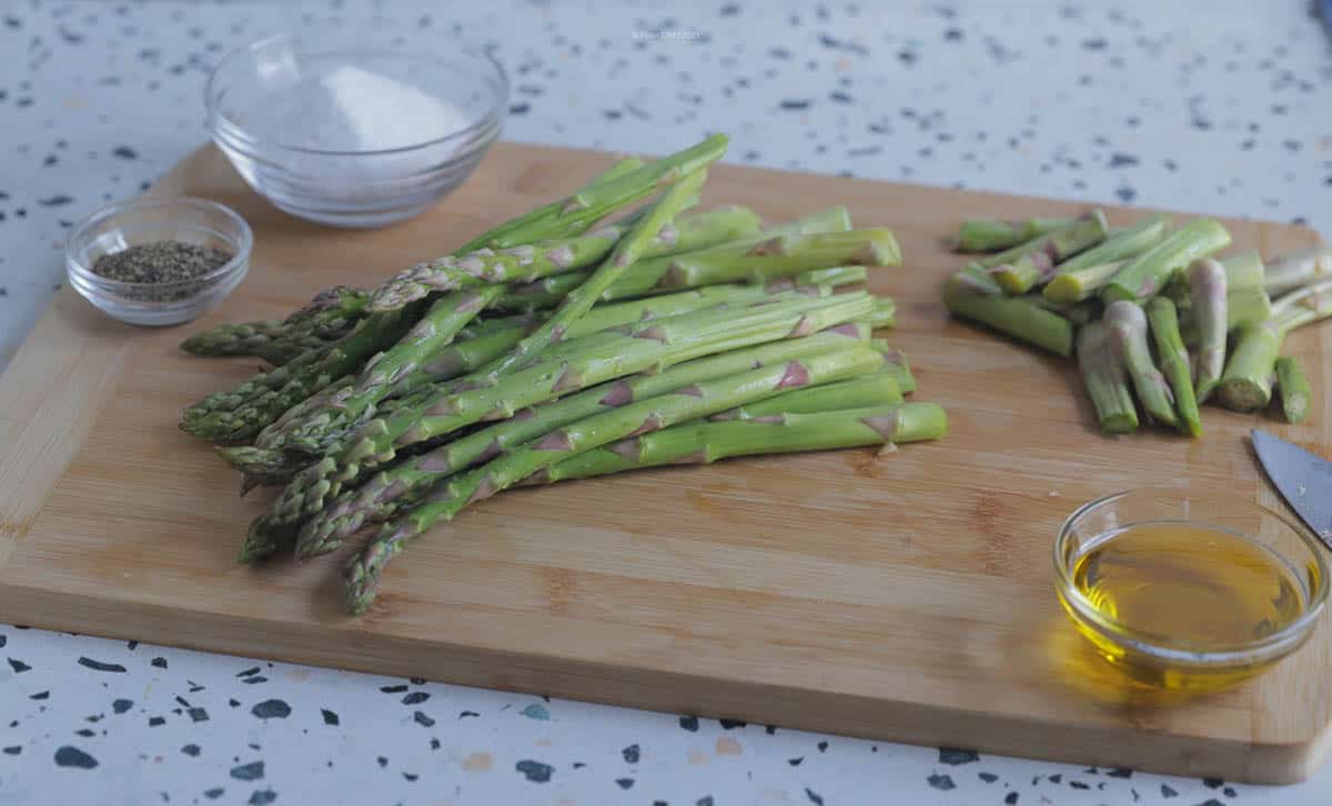 Asparagus bunch on a wooden cutting board, with ends cut off.