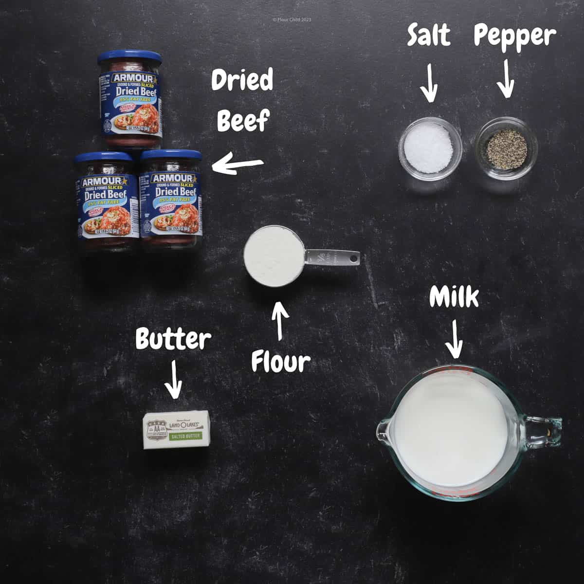 Ingredients needed to make creamed chipped beef laid out on a black table.