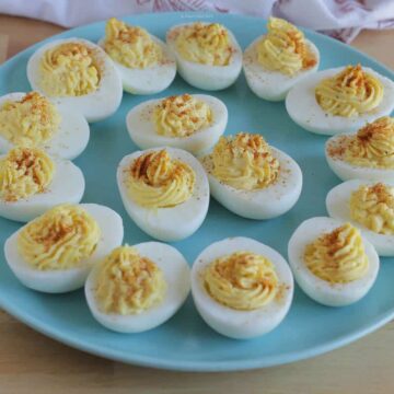 A dozen deviled eggs on a light blue serving plate.