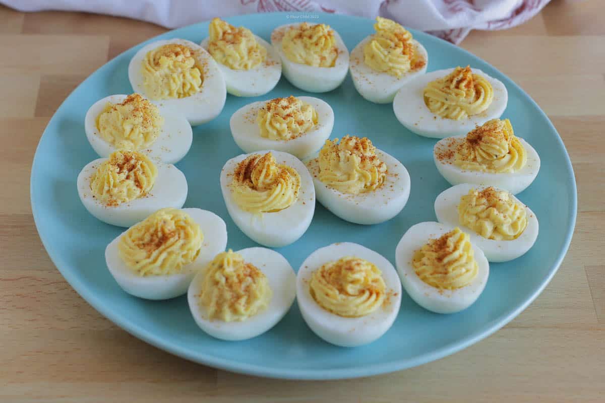 A dozen deviled eggs on a light blue serving plate.